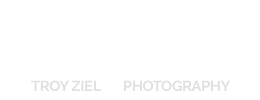 Logo featuring a minimalist camera outline with the phrase "TROY ZIEL PHOTOGRAPHY" in gray capital letters below.